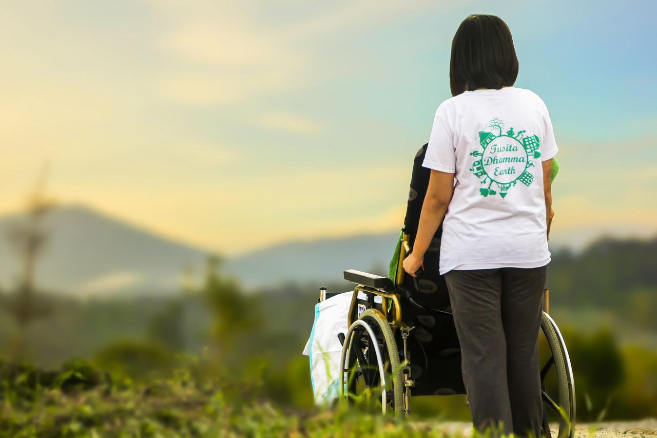 Opiekunka osoby starszej prowadząca wózek inwalidzki